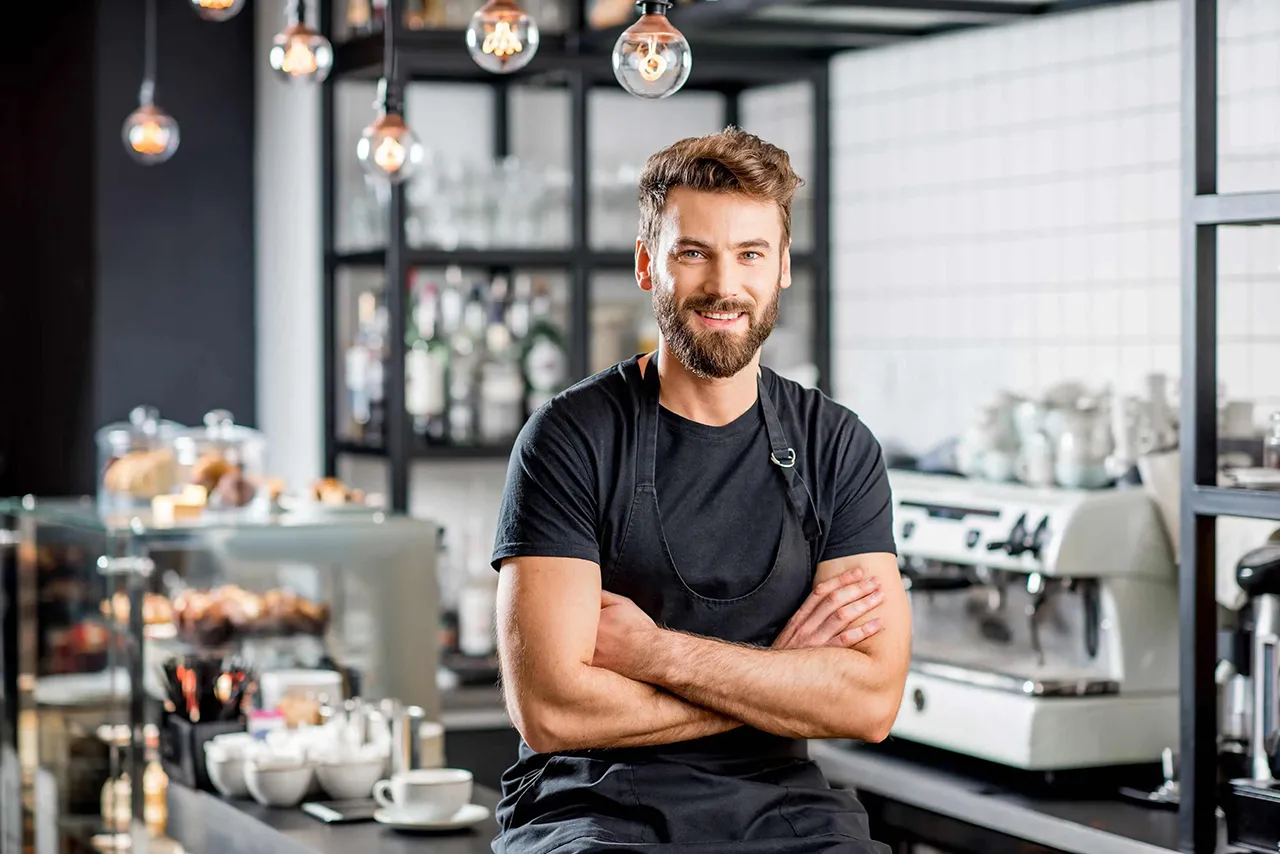 Male barista standing in front of coffee counter