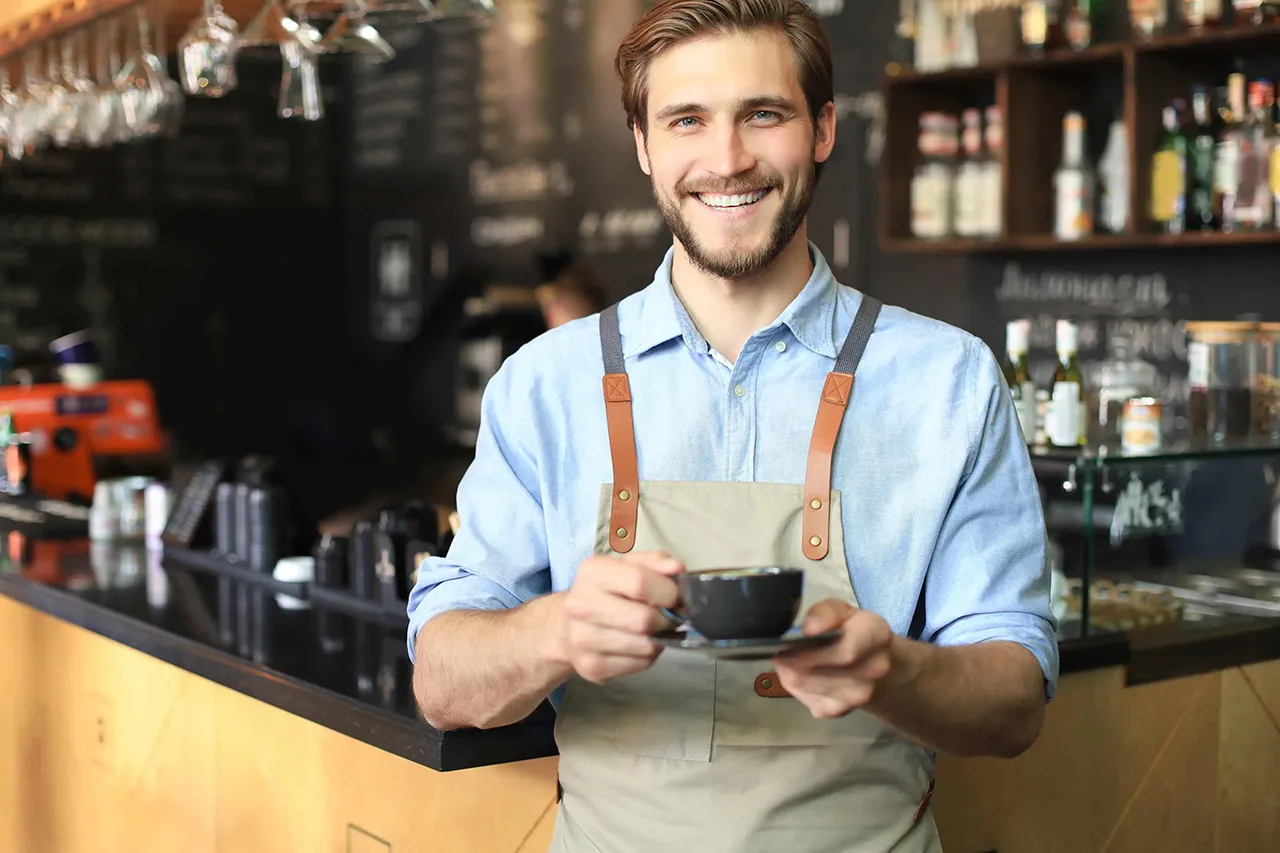 Male barista holding coffee cup